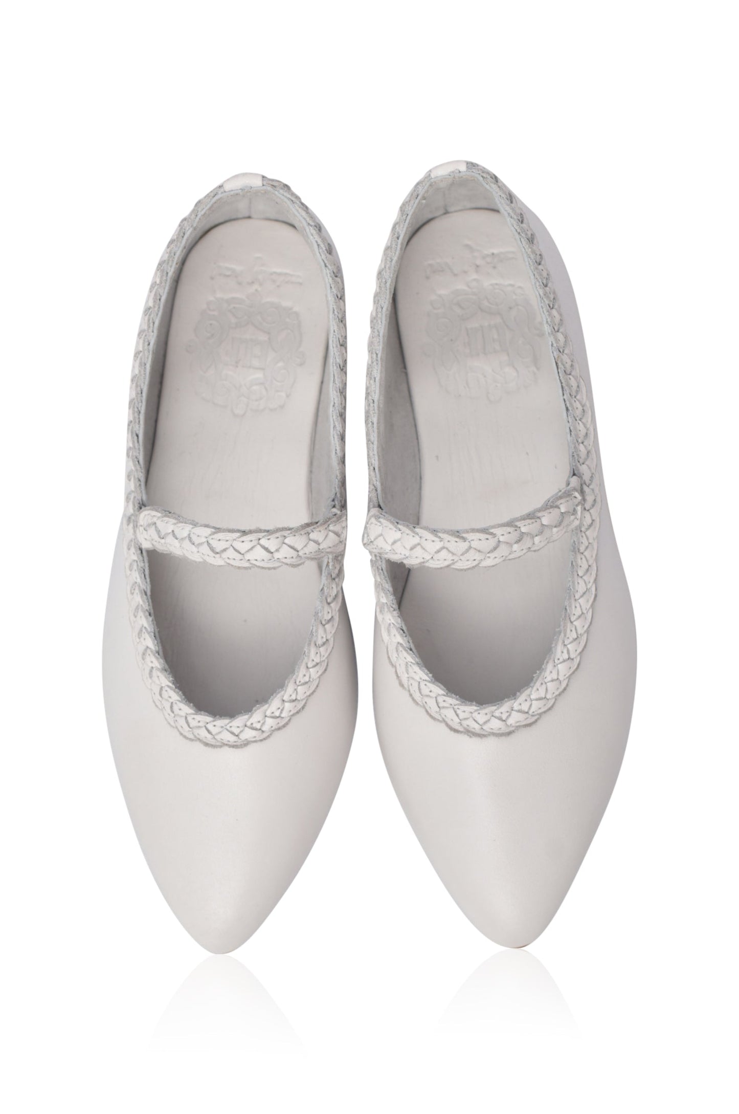 Pair of white pointed-toe shoes with braided straps on a white background