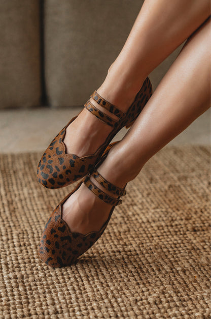Leopard print shoes worn by a person on a textured surface