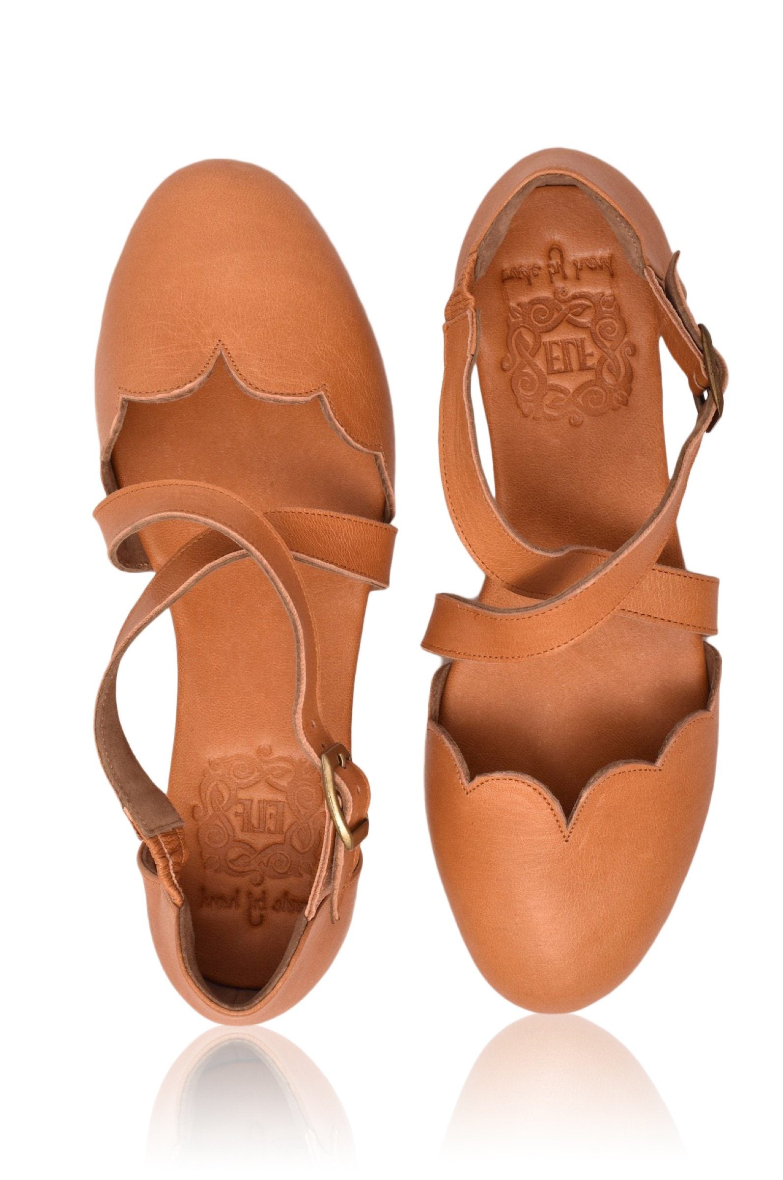 Pair of tan leather sandals with cut-out design on a white background
