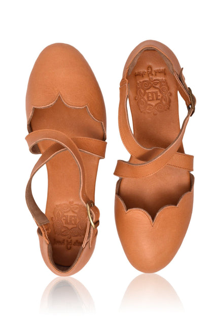 Pair of tan leather sandals with cut-out design on a white background