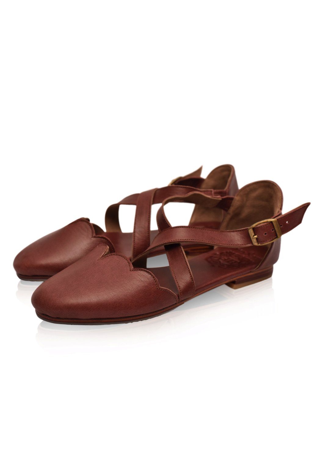 Pair of brown leather sandals with criss-cross straps on a white background