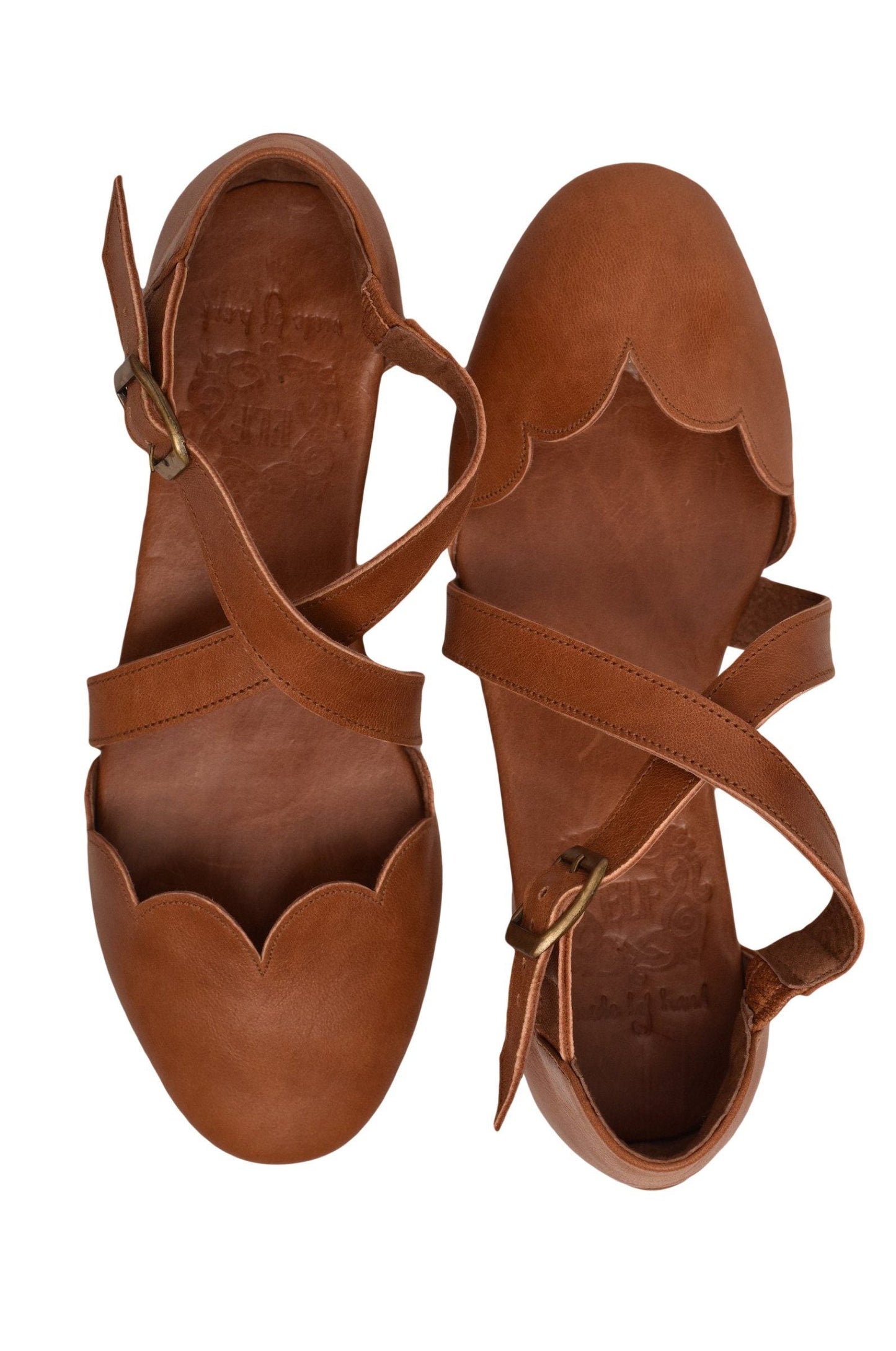 Pair of brown leather sandals with strap details on a white background
