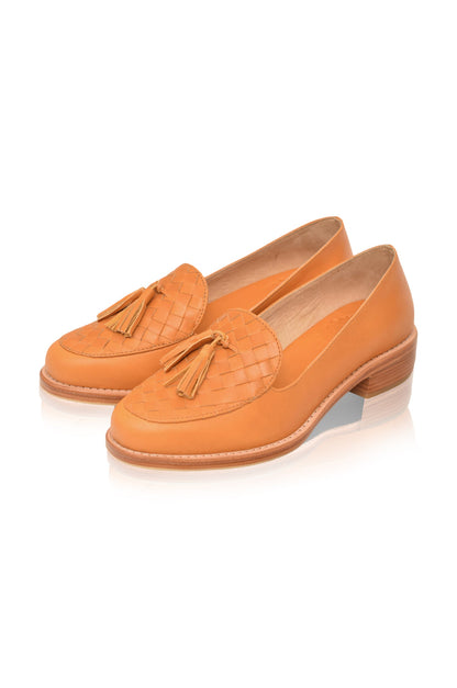Pair of orange loafers with tassels on a white background