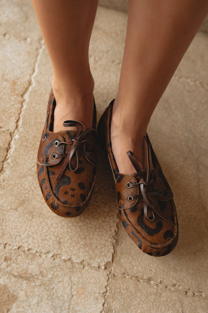 Brown leather shoes with decorative elements on a stone floor