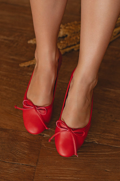 Red shoes with bows on a wooden floor