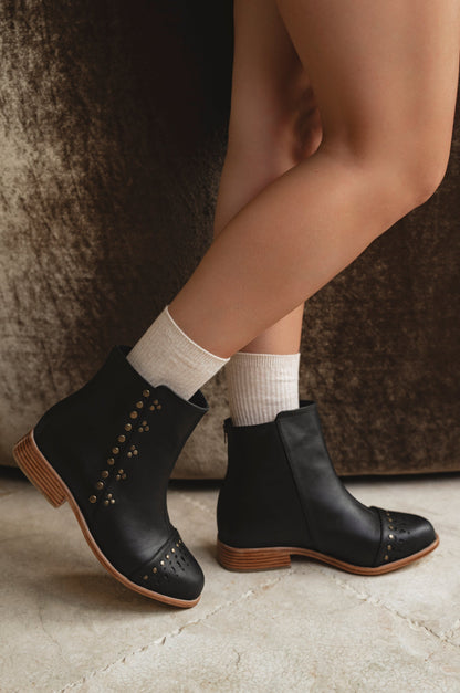 Black ankle boots with wooden soles worn with white socks on a neutral background