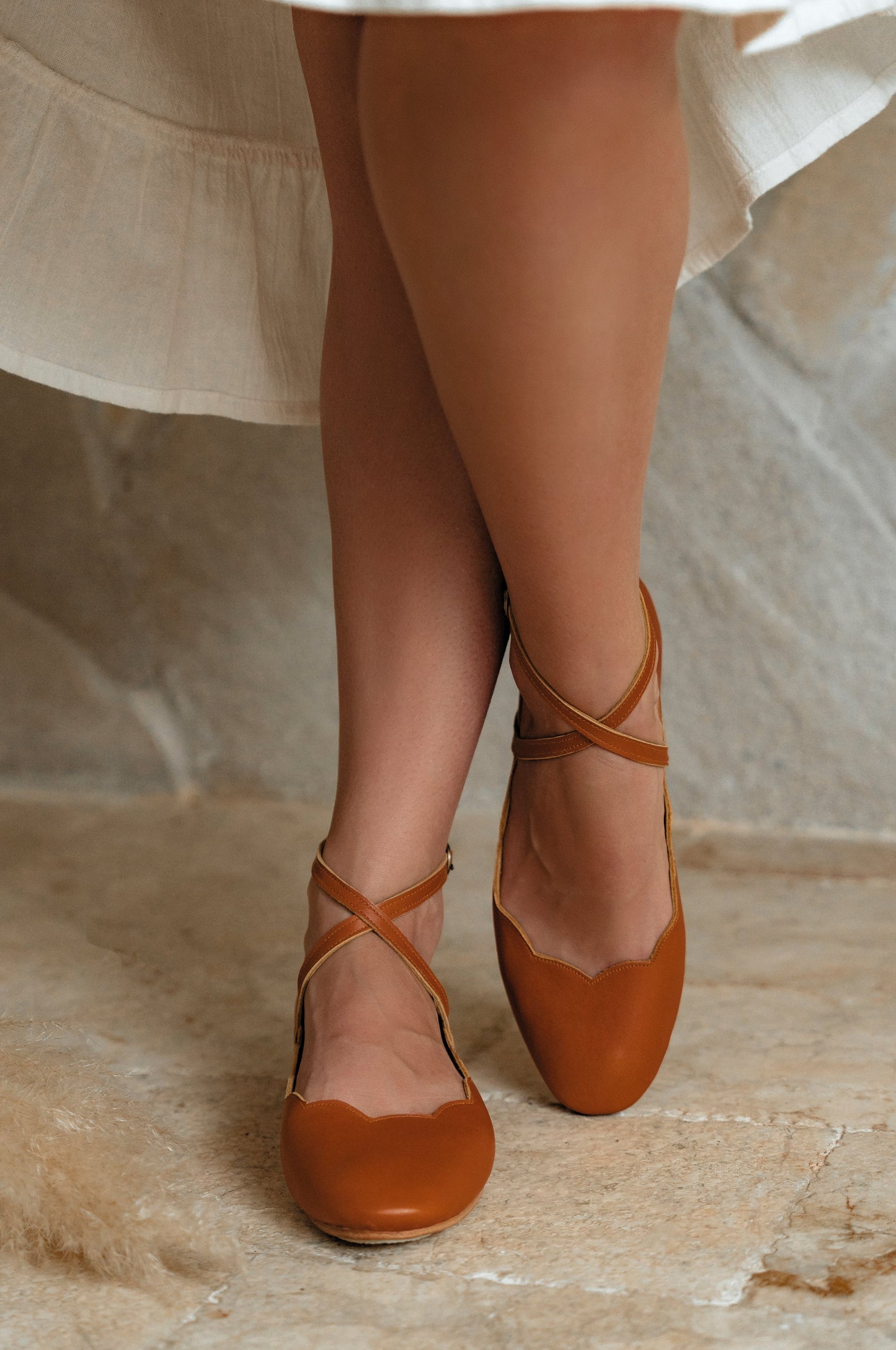 Brown ballet flats worn with sheer stockings on a neutral background
