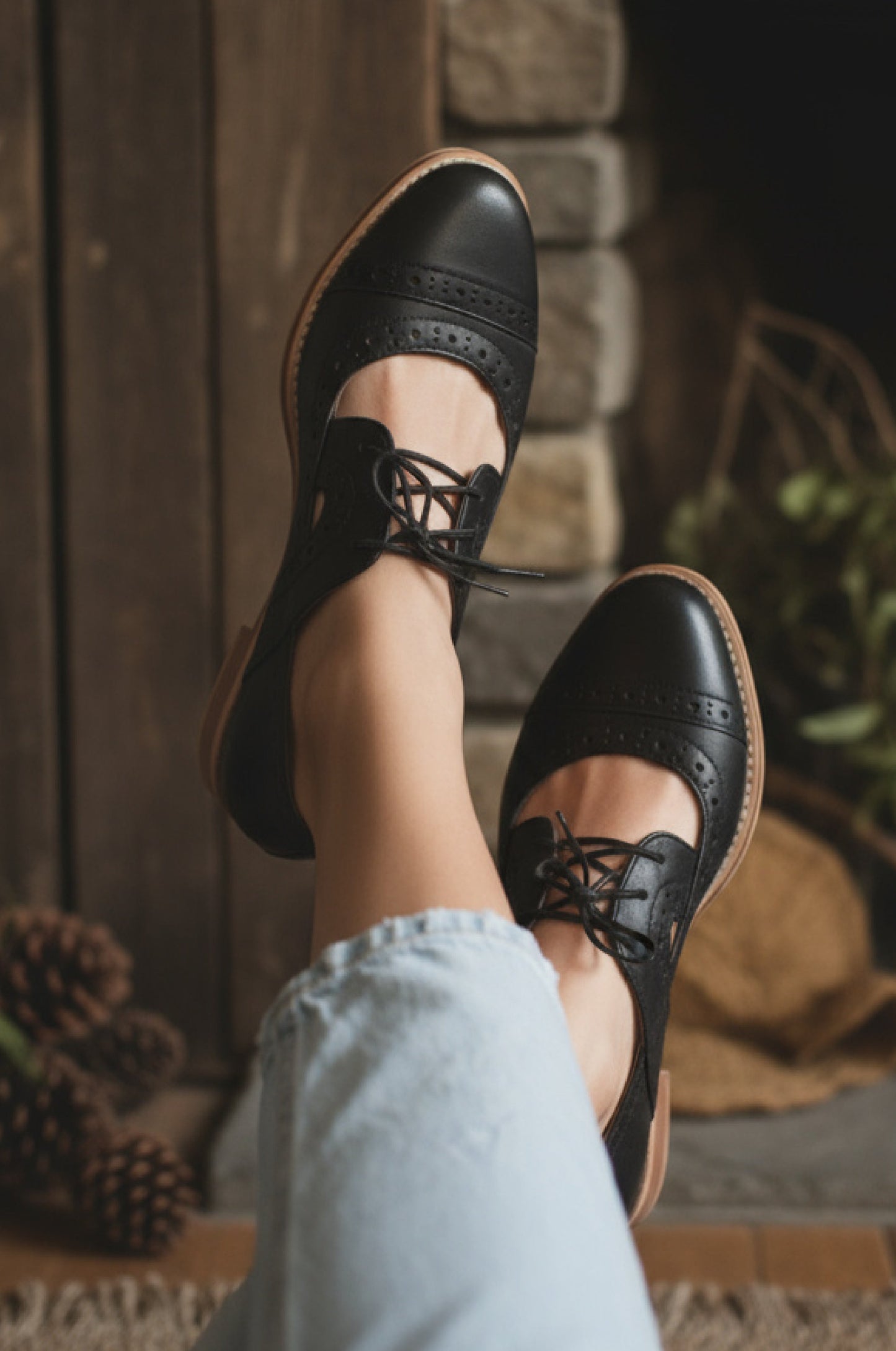Black shoes with brown soles worn by a person sitting on steps.