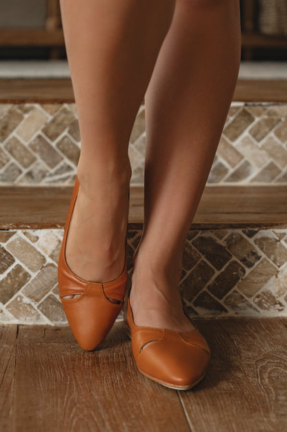 Orange shoes worn with sheer stockings on a tiled floor.