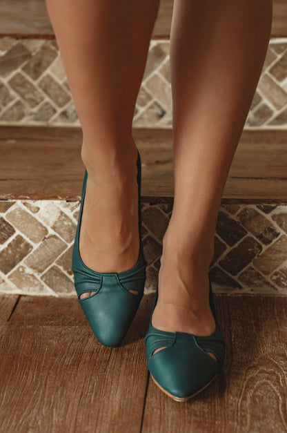 Teal shoes worn on a wooden floor with a tiled wall background
