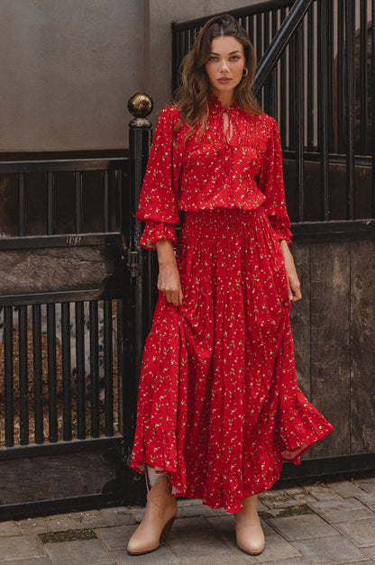 Woman wearing a red floral dress standing in the barn.